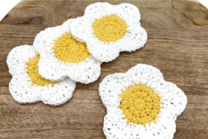 Four handmade crocheted yellow and white daisy coasters